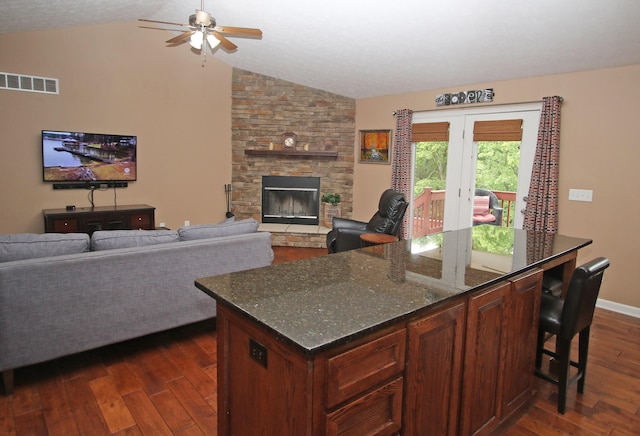 5420 Kiddville Ln, Lexington, KY 40515 - kitchen with lofted ceiling, a ceiling fan, dark wood finished floors, dark stone counters, and a stone fireplace