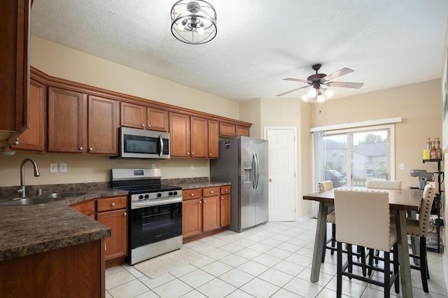 3008 Roundway Down Ln, Lexington, KY 40509 - kitchen with appliances with stainless steel finishes, a sink, dark countertops, a ceiling fan, and brown cabinetry