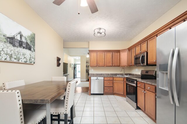 3008 Roundway Down Ln, Lexington, KY 40509 - kitchen featuring appliances with stainless steel finishes, ceiling fan, dark countertops, light tile patterned floors, and brown cabinets