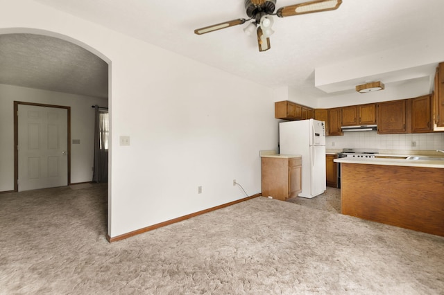 2299 Mcbrayer Rd, Clearfield, KY 40313 - kitchen with freestanding refrigerator, under cabinet range hood, light colored carpet, and brown cabinetry