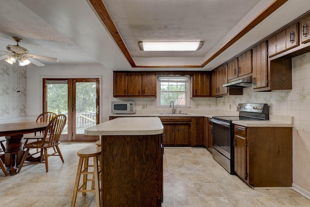 230 Fairway Dr, Nicholasville, KY 40356 - kitchen with range with electric stovetop, under cabinet range hood, white microwave, light countertops, and a tray ceiling