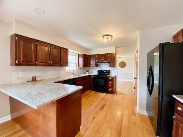 2929 Waco Rd, Lexington, KY 40503 - kitchen featuring black range with electric stovetop, freestanding refrigerator, a peninsula, light wood-style flooring, and under cabinet range hood