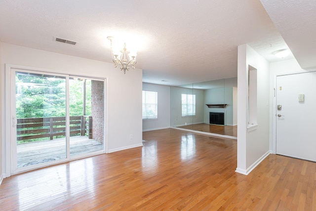 421 Redding Rd Unit 99, Lexington, KY 40517 - unfurnished living room with a chandelier, a textured ceiling, light wood-type flooring, and a fireplace