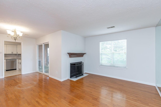 421 Redding Rd Unit 99, Lexington, KY 40517 - unfurnished living room with a chandelier, a textured ceiling, light wood-type flooring, and a fireplace with flush hearth