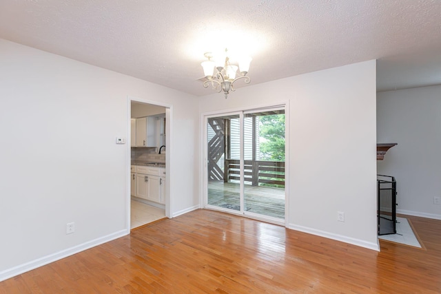 421 Redding Rd Unit 99, Lexington, KY 40517 - empty room featuring a chandelier, light wood-style flooring, and a textured ceiling