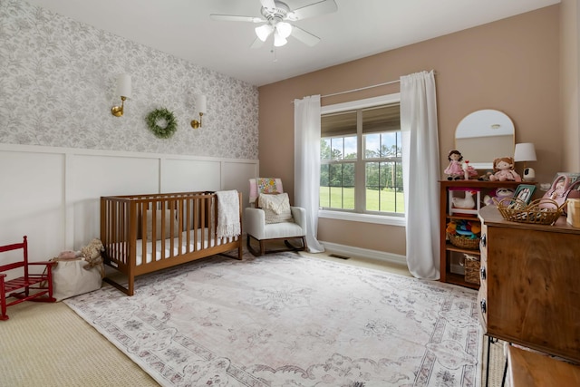 195 Couch Baker Ln, London, KY 40744 - carpeted bedroom with a crib, a wainscoted wall, a decorative wall, ceiling fan, and wallpapered walls