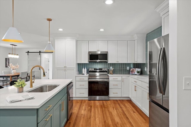 2940 Southview Dr, Lexington, KY 40503 - kitchen featuring stainless steel appliances, a barn door, white cabinetry, light countertops, and pendant lighting