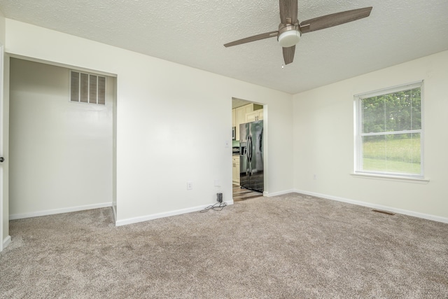 242 Possum Ridge Rd, West Liberty, KY 41472 - unfurnished bedroom featuring refrigerator with ice dispenser, carpet floors, a textured ceiling, a spacious closet, and a ceiling fan