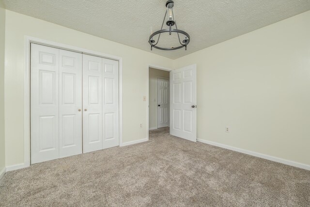 242 Possum Ridge Rd, West Liberty, KY 41472 - unfurnished bedroom featuring carpet flooring, a closet, a textured ceiling, and a chandelier