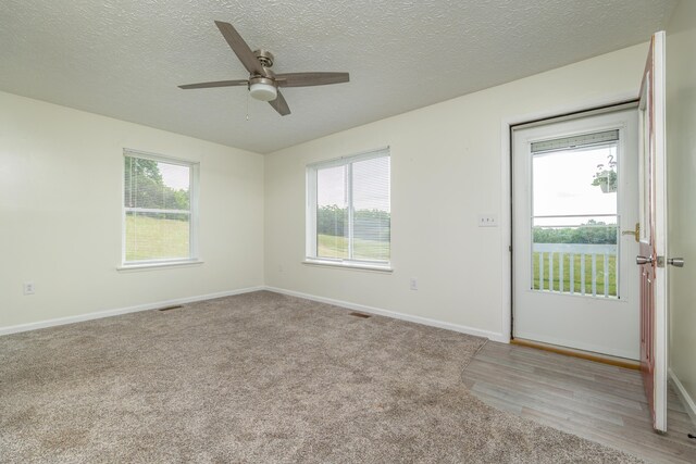 242 Possum Ridge Rd, West Liberty, KY 41472 - empty room featuring ceiling fan, a textured ceiling, light carpet, and light wood-style flooring