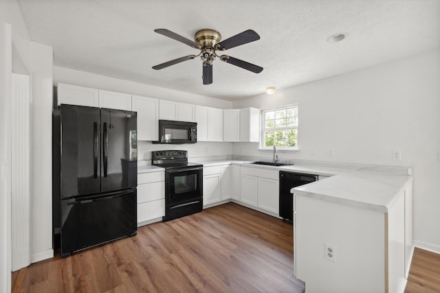 720 Pinoak Dr, Nicholasville, KY 40356 - kitchen with black appliances, a peninsula, white cabinets, light wood-style flooring, and light countertops