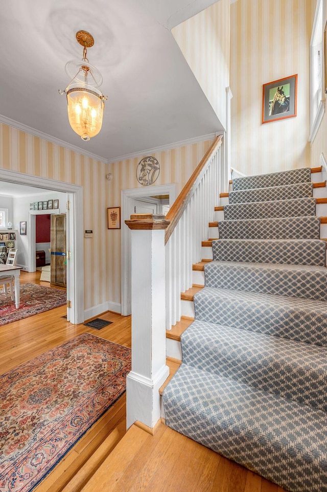315 Desha Rd, Lexington, KY 40502 - stairway featuring wallpapered walls, wood finished floors, a chandelier, and ornamental molding