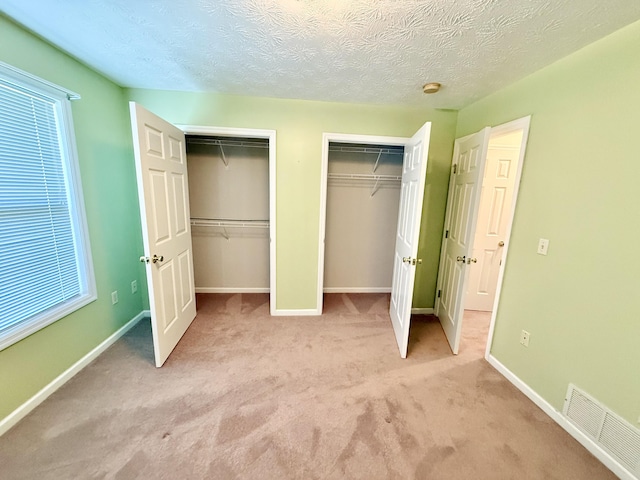 1012 Heathcliff Dr, Richmond, KY 40475 - unfurnished bedroom featuring two closets, light carpet, and a textured ceiling