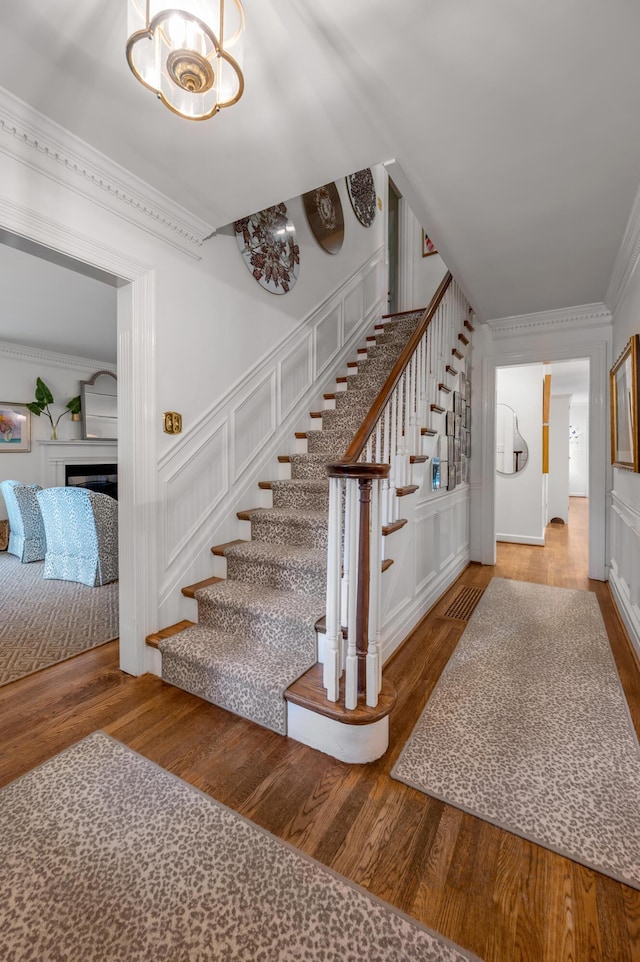 341 Kingsway Dr, Lexington, KY 40502 - stairway featuring wood finished floors, crown molding, a fireplace, and a chandelier