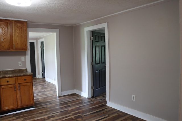2721 E Ringgold, Somerset, KY 42503 - kitchen featuring dark wood-type flooring, brown cabinetry, dark countertops, a textured ceiling, and ornamental molding
