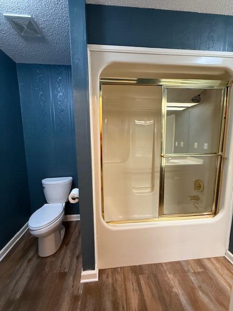 529 S 2nd St, Williamsburg, KY 40769 - bathroom with wood finished floors, bath / shower combo with glass door, and a textured ceiling