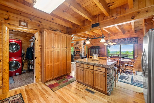 1564 High Ridge Rd, Middleburg, KY 42541 - kitchen with stacked washer and clothes dryer, wooden walls, freestanding refrigerator, light wood-type flooring, and a chandelier