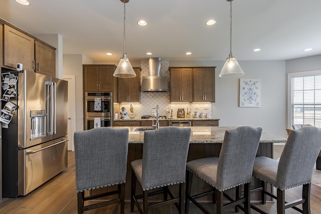 3536 Night Heron Way, Lexington, KY 40515 - kitchen with appliances with stainless steel finishes, wall chimney range hood, tasteful backsplash, light stone counters, and dark wood-style flooring