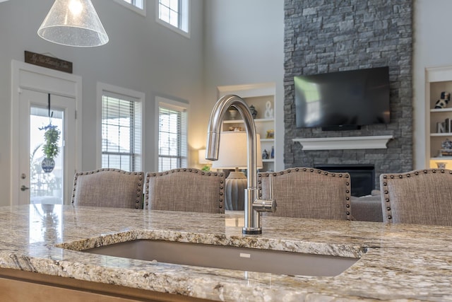 3536 Night Heron Way, Lexington, KY 40515 - kitchen with light stone counters, a stone fireplace, built in features, a towering ceiling, and open floor plan
