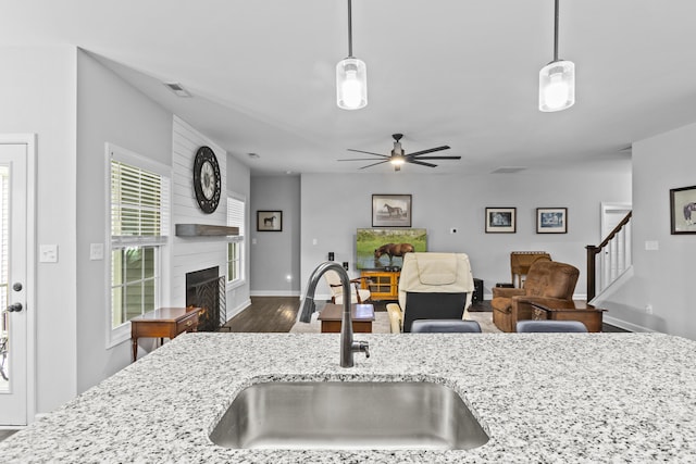 111 Kara Bryn Cv, Georgetown, KY 40324 - kitchen with a fireplace, light stone countertops, decorative light fixtures, and dark wood finished floors