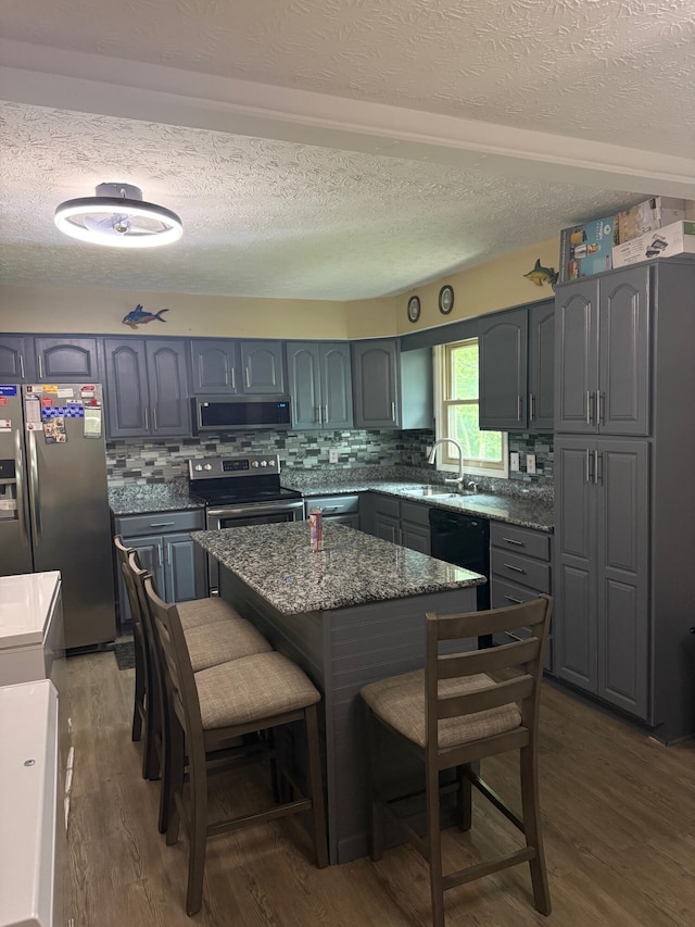 2829 Easthills Dr, Lexington, KY 40517 - kitchen with stainless steel appliances, wood finished floors, a kitchen bar, a textured ceiling, and backsplash