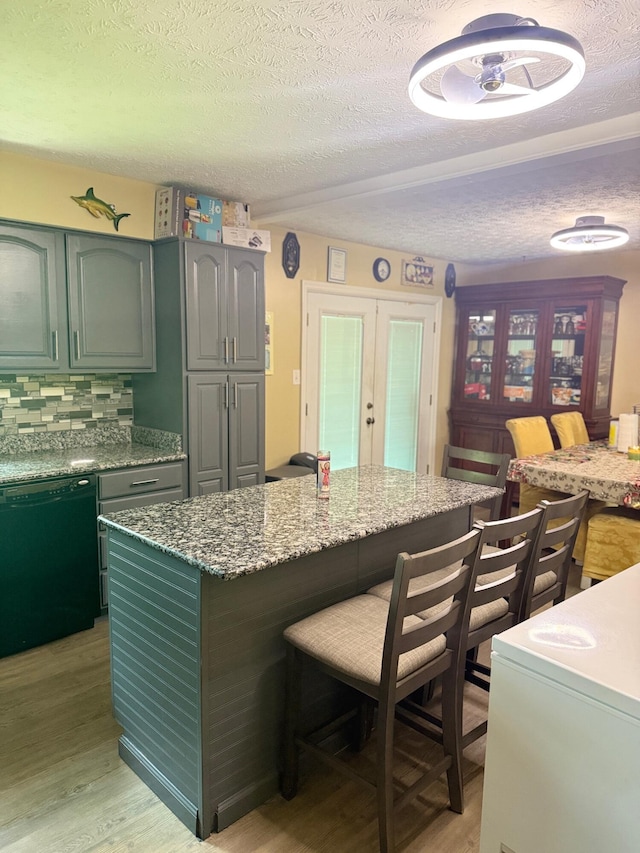 2829 Easthills Dr, Lexington, KY 40517 - kitchen with black dishwasher, light wood-type flooring, a kitchen breakfast bar, tasteful backsplash, and a textured ceiling