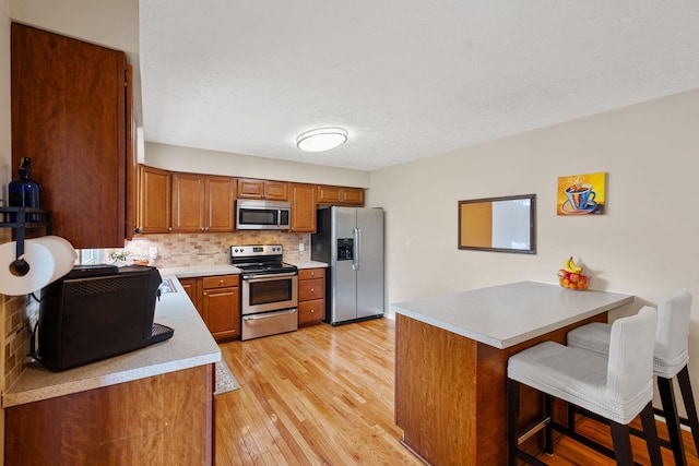 441 Cromwell Way, Lexington, KY 40503 - kitchen with appliances with stainless steel finishes, a peninsula, decorative backsplash, brown cabinetry, and a breakfast bar