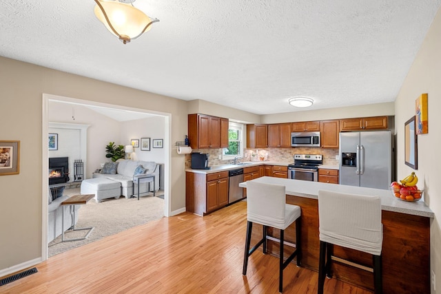 441 Cromwell Way, Lexington, KY 40503 - kitchen featuring appliances with stainless steel finishes, light wood finished floors, a textured ceiling, a kitchen breakfast bar, and light countertops