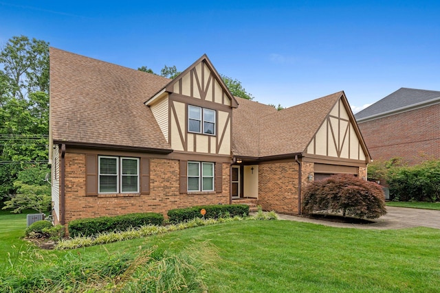 3605 Afton Pl, Lexington, KY 40515 - tudor-style house featuring roof with shingles, brick siding, an attached garage, driveway, and a front yard