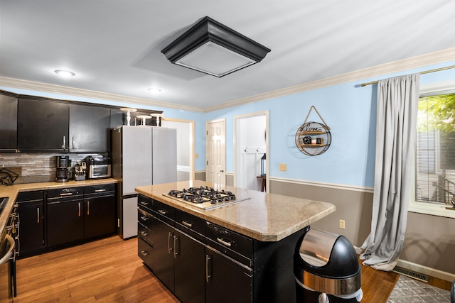 1211 Forest Circle Dr, Corbin, KY 40701 - kitchen featuring stainless steel gas cooktop, light countertops, crown molding, light wood finished floors, and decorative backsplash