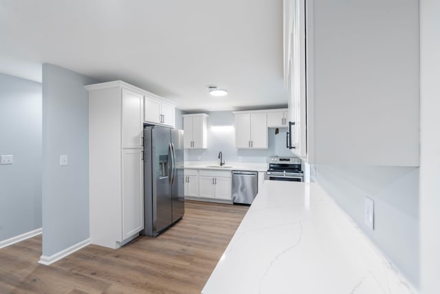 423 Perryville St, Harrodsburg, KY 40330 - kitchen featuring appliances with stainless steel finishes, white cabinetry, light stone countertops, and light wood-style flooring