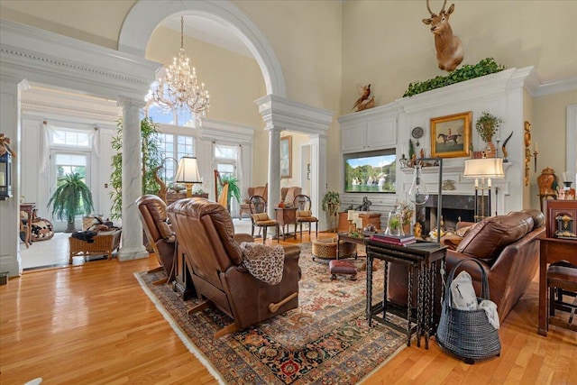 5045 Van Meter Rd, Winchester, KY 40391 - living room featuring decorative columns, light wood-style floors, a towering ceiling, a fireplace, and ornamental molding