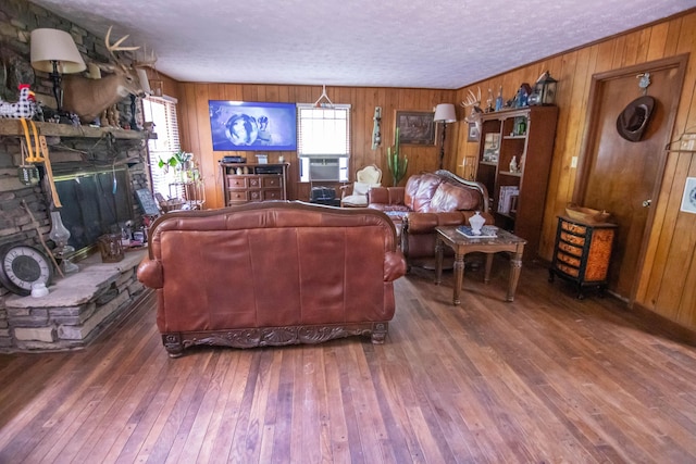 1181 Tracy Rd, Lawrenceburg, KY 40342 - living room featuring wood walls, wood-type flooring, a stone fireplace, and a textured ceiling