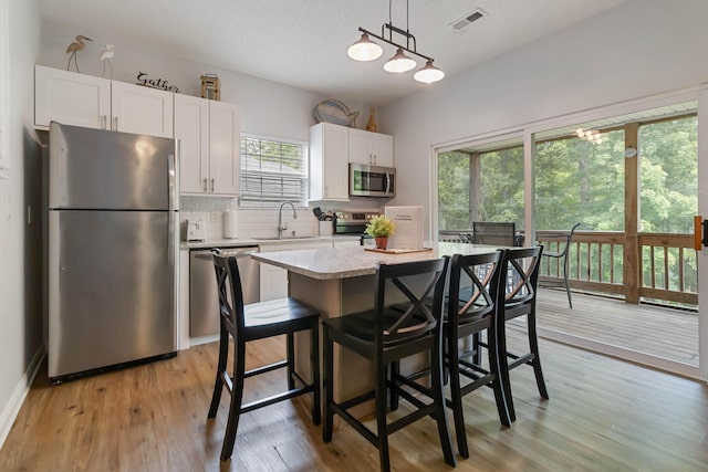 2394 Roberts Bend Rd, Burnside, KY 42519 - kitchen with appliances with stainless steel finishes, tasteful backsplash, white cabinetry, a center island, and light wood finished floors