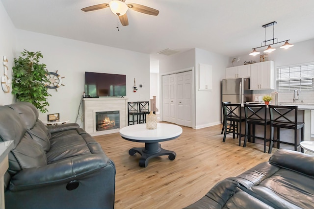 2394 Roberts Bend Rd, Burnside, KY 42519 - living area featuring a ceiling fan, light wood finished floors, and a glass covered fireplace