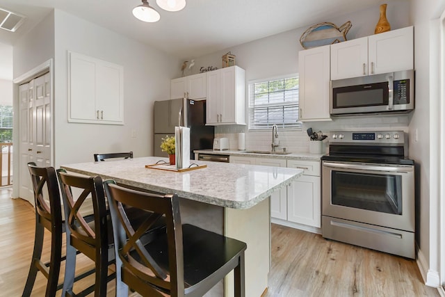2394 Roberts Bend Rd, Burnside, KY 42519 - kitchen featuring stainless steel appliances, a breakfast bar, light wood finished floors, and a kitchen island