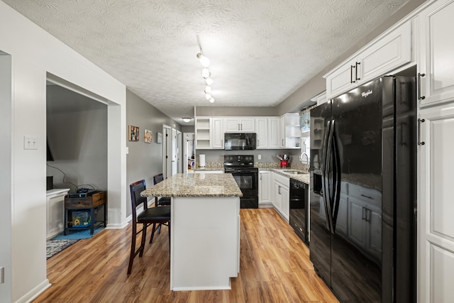 215 New Dixville Rd, Harrodsburg, KY 40330 - kitchen with black appliances, open shelves, light wood-style flooring, a center island, and white cabinetry