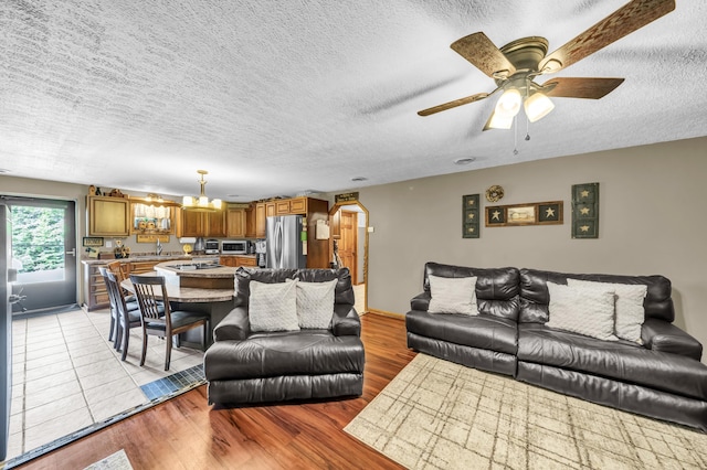 72 Blevins Ln, Vanceburg, KY 41179 - living area featuring a chandelier, a textured ceiling, ceiling fan, light wood-type flooring, and arched walkways