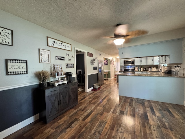 190 Keeneland Trl, Corbin, KY 40701 - kitchen with appliances with stainless steel finishes, dark wood-style flooring, a peninsula, dark countertops, and a textured ceiling