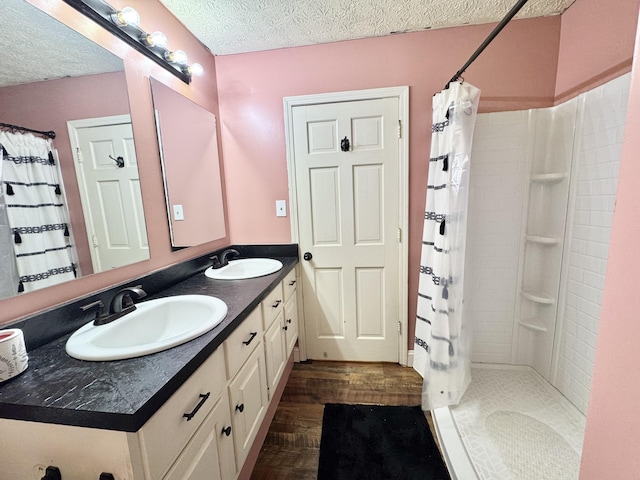 190 Keeneland Trl, Corbin, KY 40701 - bathroom featuring wood finished floors, a textured ceiling, a tile shower, and double vanity