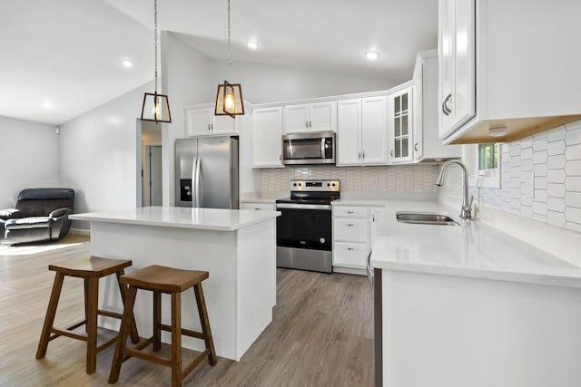 168 Kentucky Ln, Pine Knot, KY 42635 - kitchen with stainless steel appliances, vaulted ceiling, a kitchen island, decorative backsplash, and wood finished floors