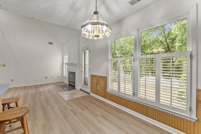 1048 Vero Ct, Lexington, KY 40509 - unfurnished living room featuring wood finished floors, vaulted ceiling, a chandelier, a fireplace with flush hearth, and a wainscoted wall