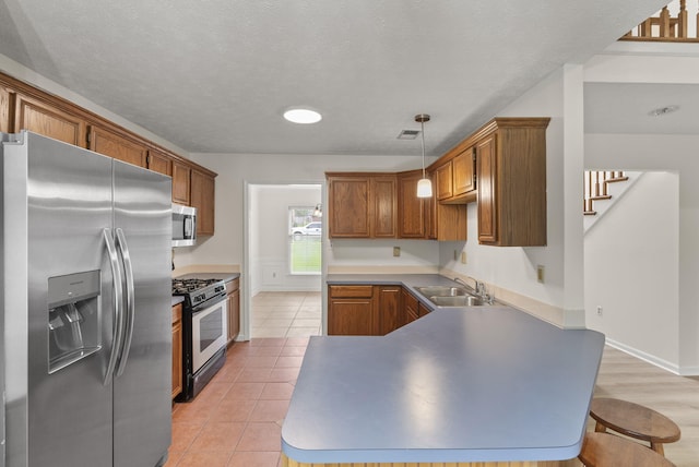 1048 Vero Ct, Lexington, KY 40509 - kitchen featuring stainless steel appliances, a peninsula, brown cabinets, light tile patterned floors, and pendant lighting