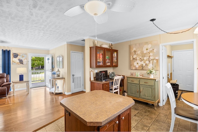 1809 Pine Top Rd, London, KY 40741 - kitchen featuring open floor plan, ornamental molding, glass insert cabinets, a ceiling fan, and brown cabinetry