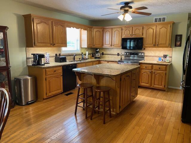 407 Autumn Dr, Lancaster, KY 40444 - kitchen featuring black appliances, a ceiling fan, light wood-style floors, tasteful backsplash, and a textured ceiling