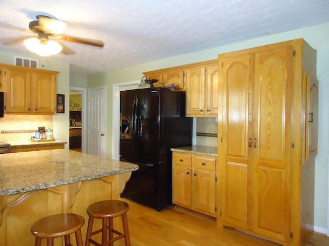 407 Autumn Dr, Lancaster, KY 40444 - kitchen featuring black fridge with ice dispenser, a ceiling fan, tasteful backsplash, light stone counters, and a textured ceiling