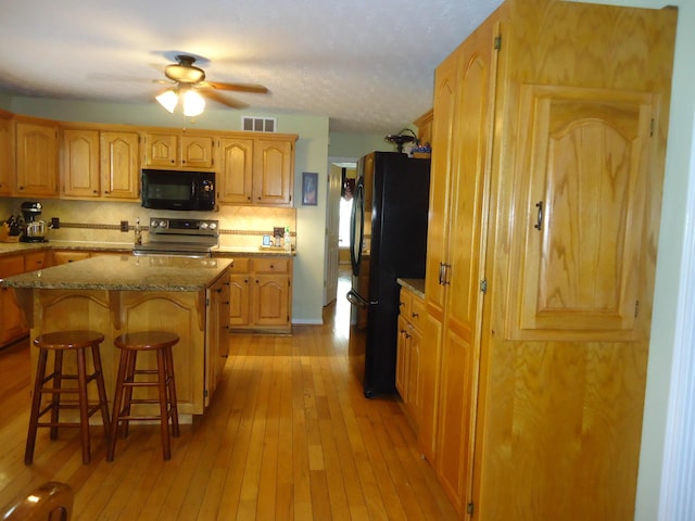 407 Autumn Dr, Lancaster, KY 40444 - kitchen featuring black appliances, a kitchen bar, light wood-type flooring, a ceiling fan, and backsplash