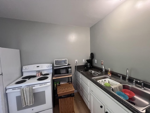 195 Copperhead Rd, Corbin, KY 40701 - kitchen with electric range, stainless steel microwave, white cabinetry, dark countertops, and wood finished floors