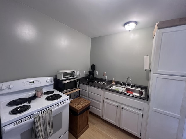 195 Copperhead Rd, Corbin, KY 40701 - kitchen with white electric stove, stainless steel microwave, white cabinets, dark countertops, and light wood-style floors