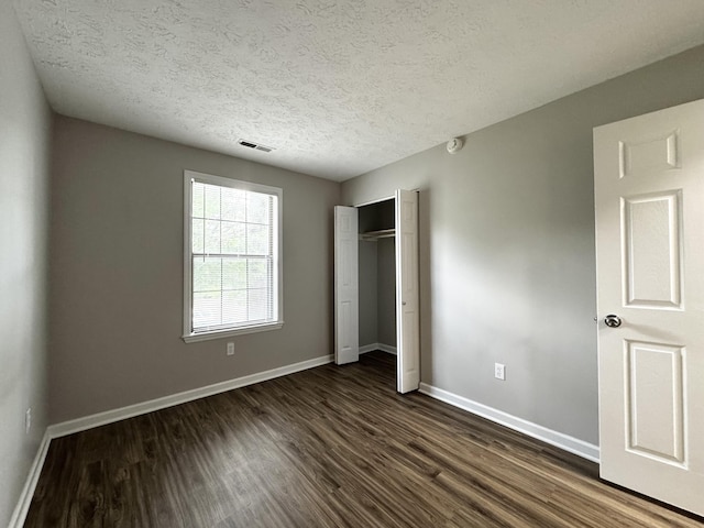 404 Bainbridge Ct Unit E3, Lexington, KY 40509 - unfurnished bedroom featuring dark wood-style flooring, a closet, and a textured ceiling